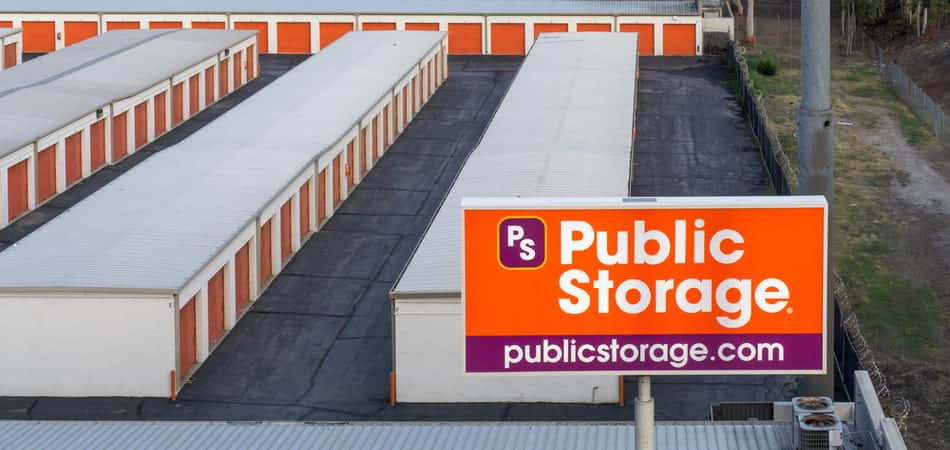 a public storage facility with rows of external storage units with orange roll up doors